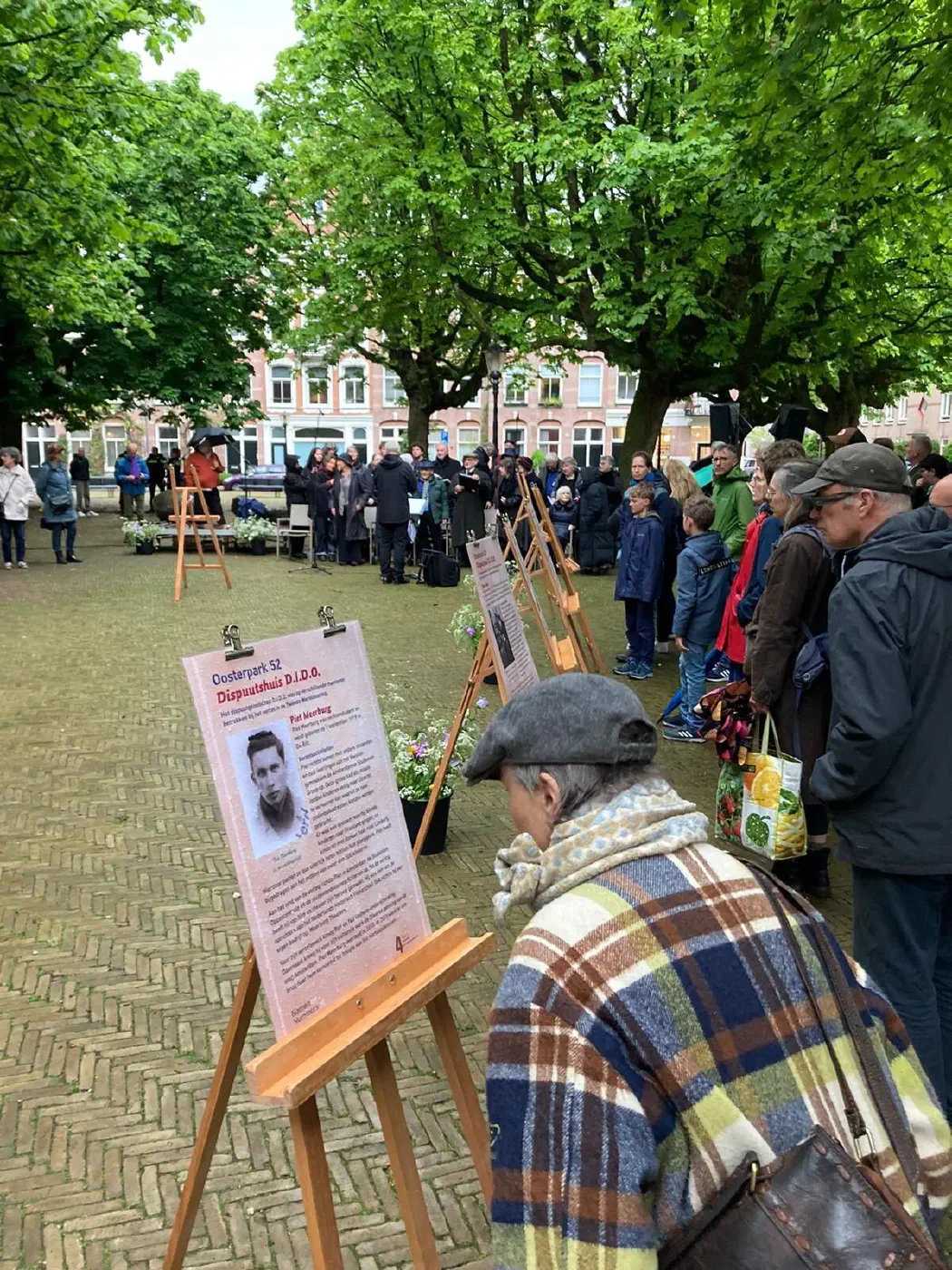 Bezoeker leest de gedenkposter over Dispuutshuis D.I.D.O. op een ezel