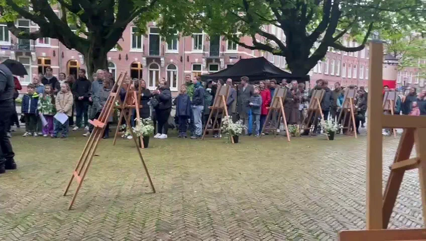 Publiek staat in een halve kring achter een rij ezels met gedenkposters