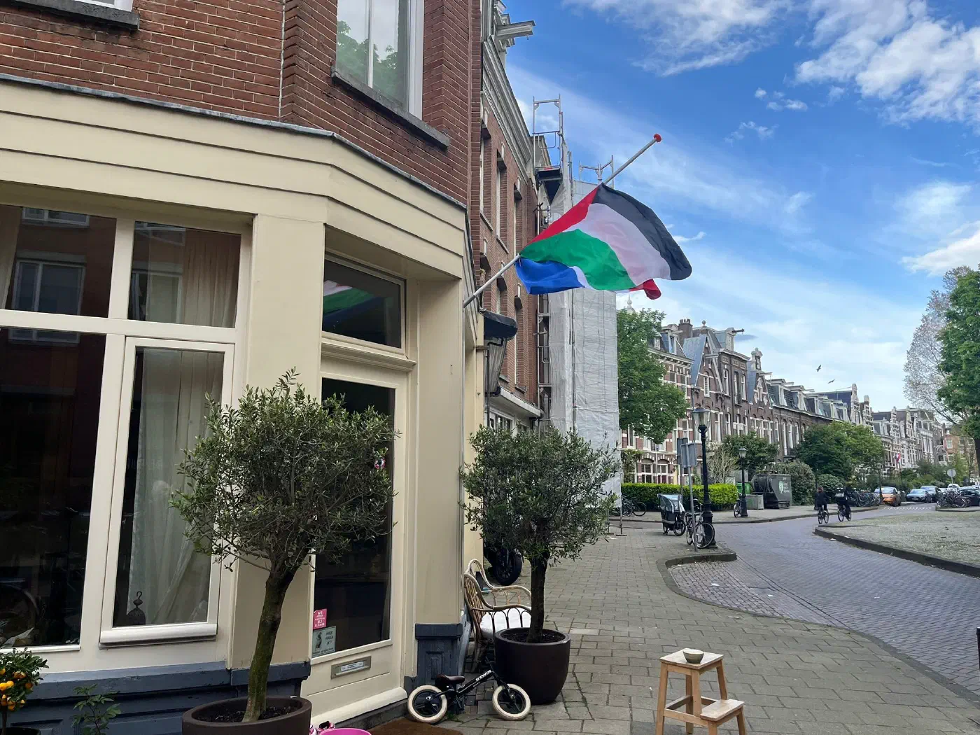 Halfstok hangende vlag aan de gevel van een hoekhuis in de buurt