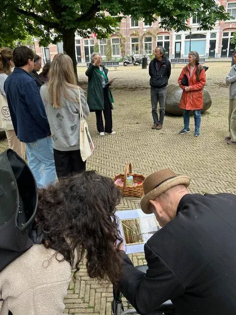 Rondleidingsgroep staat in een kring op een plein en luistert naar een gids