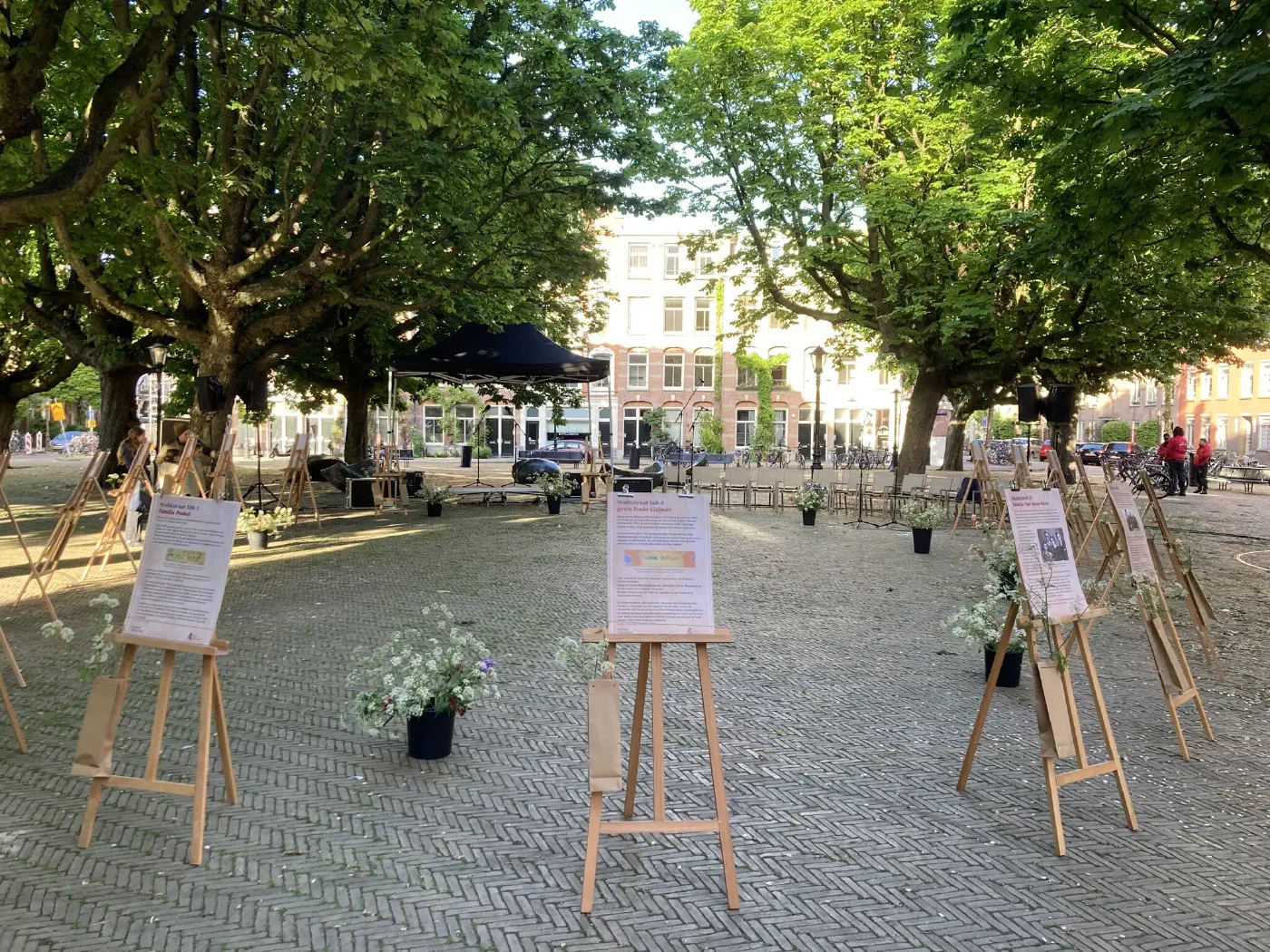 Leeg Kastanjeplein vooraf, met gedenkposters op ezels, bloemen en een podiumtent