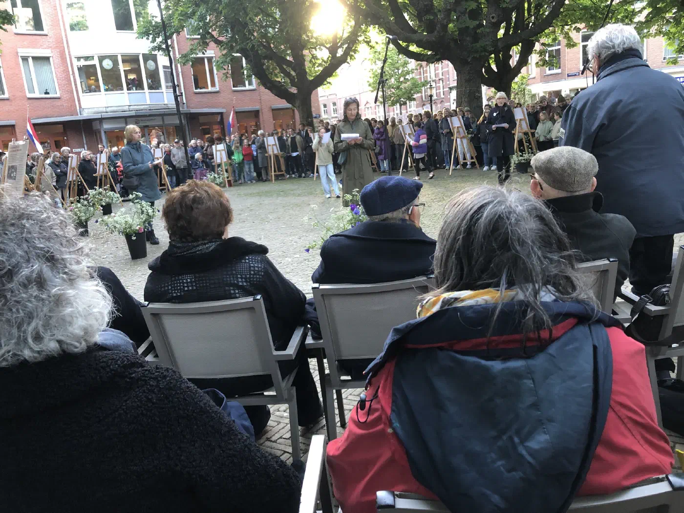 Vrouw leest voor op het plein, gezien vanaf de stoelen van het publiek