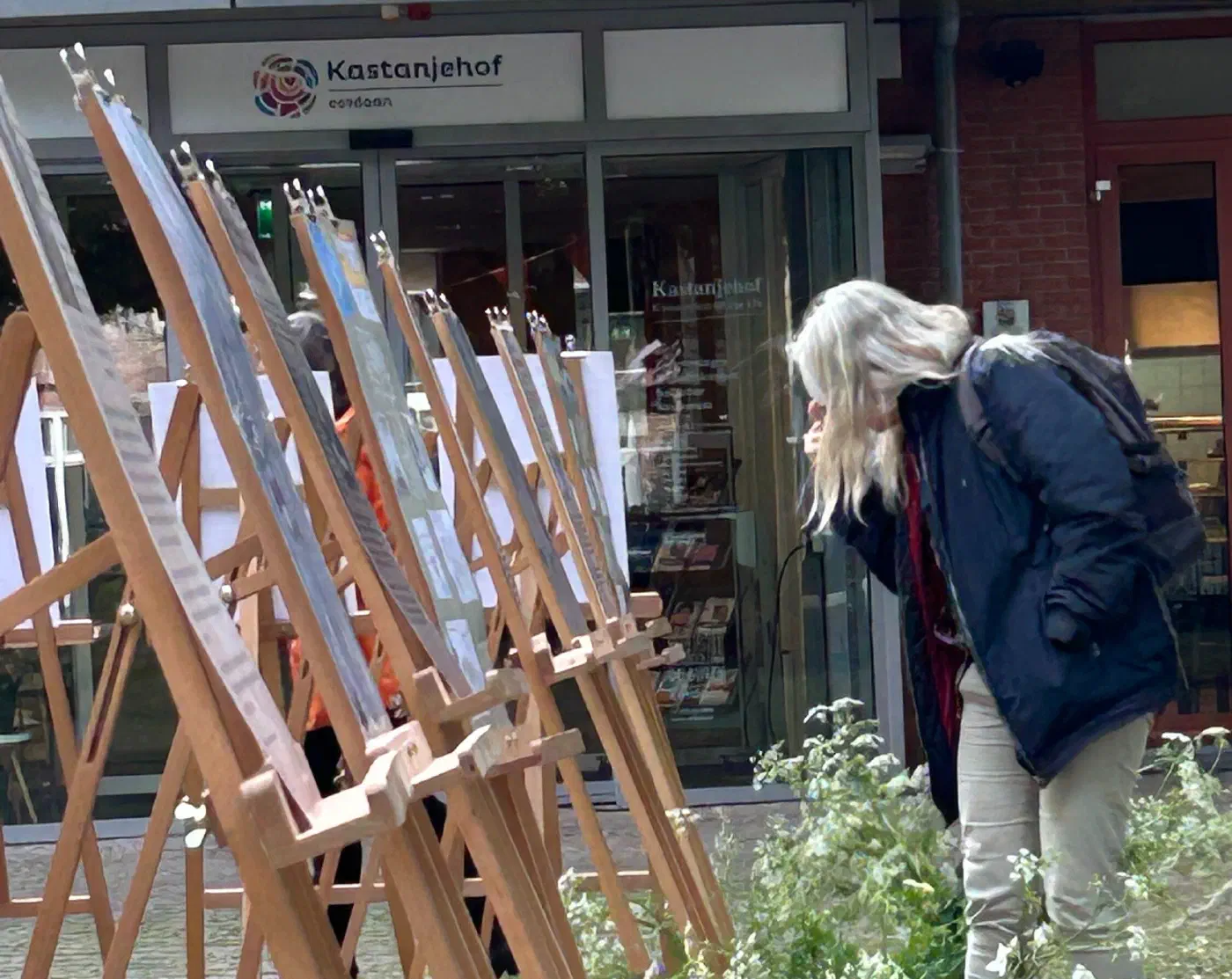 Bezoeker buigt zich over een gedenkposter op een ezel bij de Kastanjehof