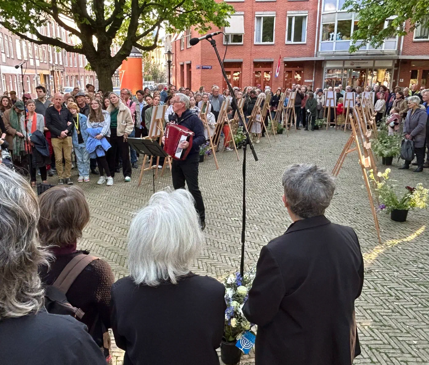 Accordeonist voor een grote menigte en gedenkposters op schildersezels op het Kastanjeplein