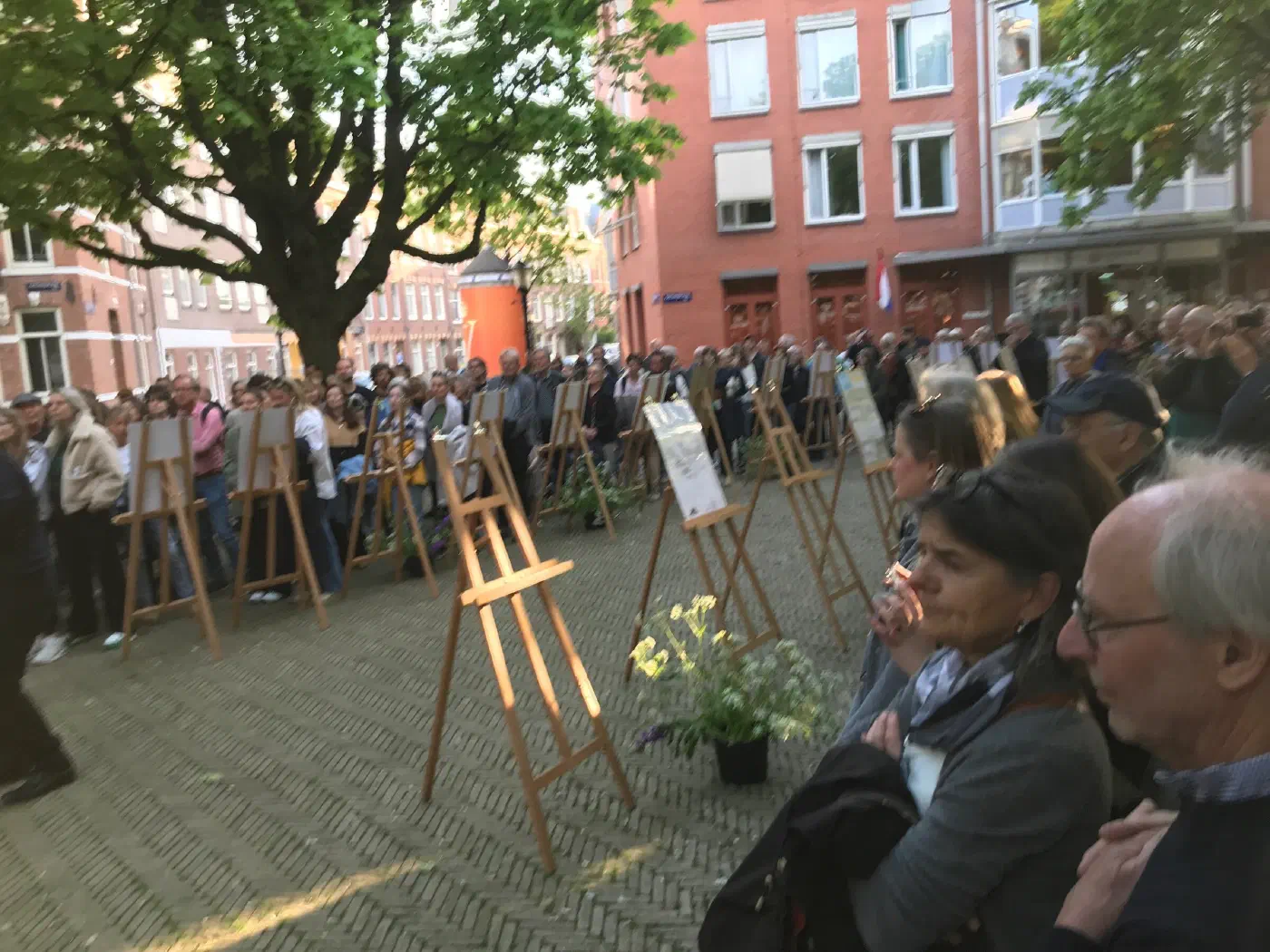 Publiek rond schildersezels met gedenkposters op het Kastanjeplein tijdens 4 mei