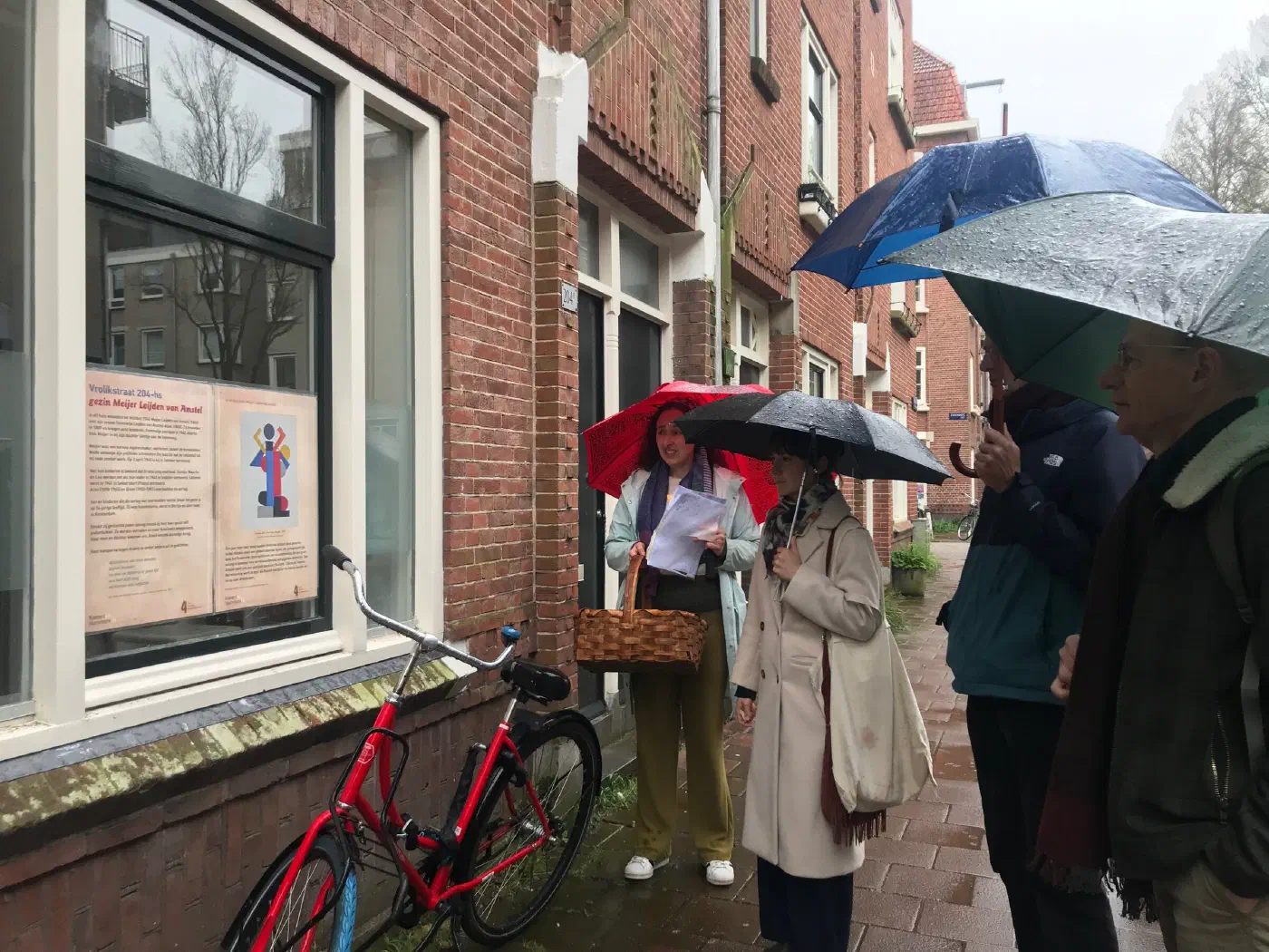 Gids met paraplu vertelt bij de gedenkposter voor gezin Meijer Leijden van Amstel, Vrolikstraat 204